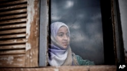 A Syrian girl from Aleppo looks outside a window of an abandoned building where her and several families took refuge due to fighting between Free Syrian Army fighters and government forces in the northeastern city of Qamishli, Syria, Thursday, Feb. 28, 2013. (AP Photo/Manu Brabo)