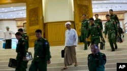 In this Sept. 17, 2014 photo, a member of Myanmar’s Lower House with a silk turban known as a "gaun baun," leaves Myanmar’s Upper House in Naypyidaw, Myanmar. The civilians elected to Myanmar’s bicameral legislature are required to wear hats when taking the floor. Their appointed military colleagues are not. (AP Photo/Gemunu Amarasinghe)