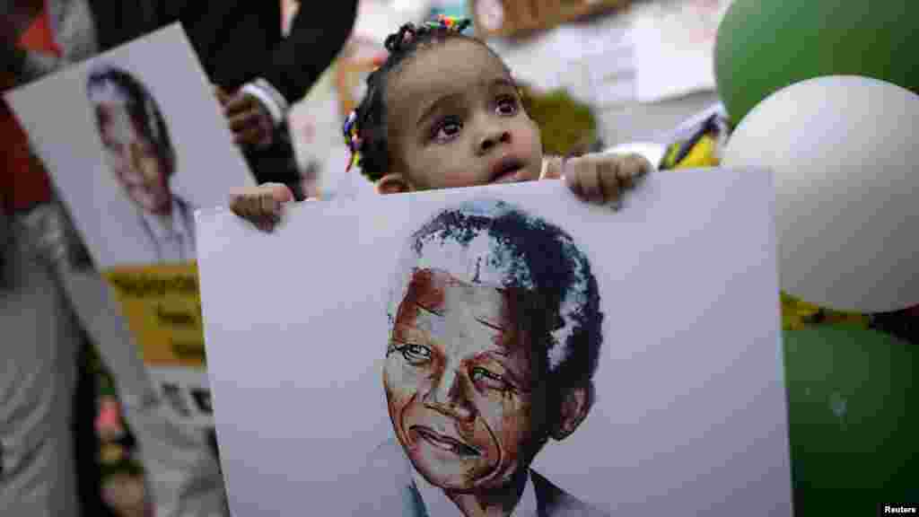 Two-year-old Precious Mali holds a picture of former South African President Mandela.