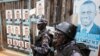 FILE - Policemen stand in front of the gate of opposition leader Kizza Besigye's office in Kampala, Uganda.