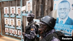 FILE - Policemen stand in front of the gate of opposition leader Kizza Besigye's office in Kampala, Uganda.