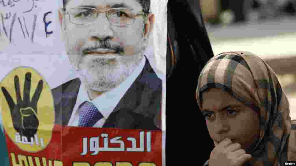 A supporter of Egyptian President Mohamed Morsi stands next to a poster of Morsi during a protest outside the police academy, Nov. 4, 2013.