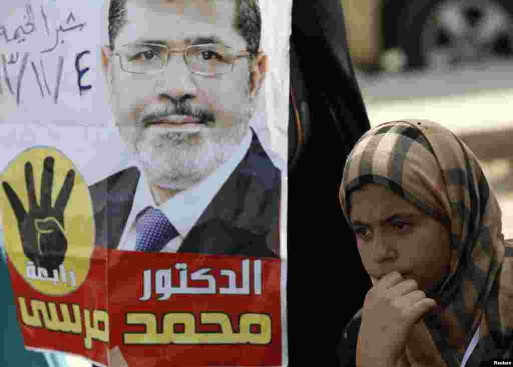 A supporter of the Muslim Brotherhood and ousted Egyptian President Mohamed Morsi stands next to a poster of Morsi during a protest outside the police academy, Nov. 4, 2013.