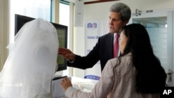 U.S. Secretary of State John Kerry looks at a wedding dress created by Lihn Thai, front, founder and CEO of The One Couture, during a business event in Ho Chi Minh City, Vietnam Saturday, Dec. 14, 2013. 