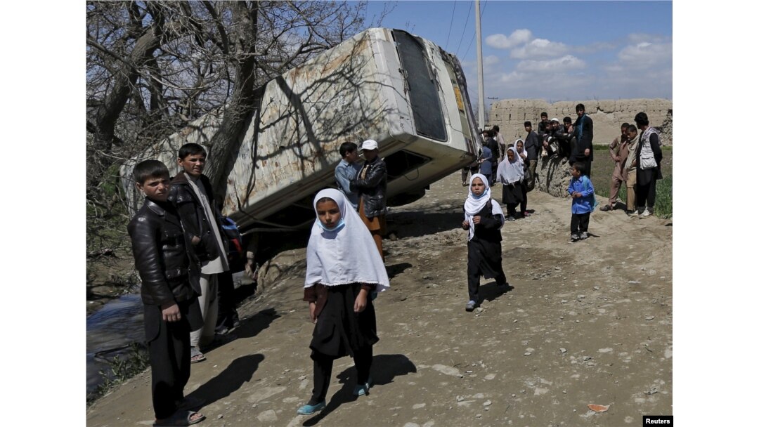 Schoolgirls walk past a damaged mini-bus after it was hit by a bomb blast in the Bagrami district of Kabul, Afghanistan April 11, 2016.