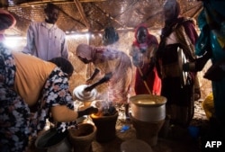 FILE - Women use fuel-efficient cook stoves make their meals in a food distribution center in the Rwanda camp for internally displaced people (IDP) in Tawila, North Darfur, March 4, 2014.