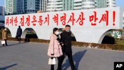 북한 평양 류경체육관 인근에 설치된 김정은 국무위원장 찬양 표어 앞으로 주민들이 지나가고 있다. (자료사진)