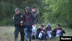 FILE - U.S. Border Patrol agents apprehend undocumented migrants after they illegally crossed the U.S.-Mexico border in Mission, Texas, April 9, 2019.