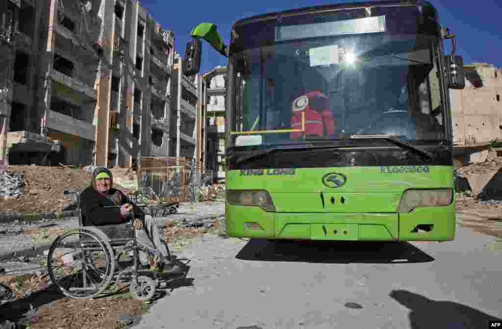 An elderly Syrian woman in a wheelchair waits next to a bus during an evacuation operation of rebel fighters and their families from rebel-held neighborhoods in the embattled city of Aleppo on Dec. 15, 2016.