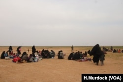 Women gather to receive humanitarian aid while they wait for transport to overcrowded Syrian camps, near Baghuz in Deir el-Zour, Syria, Feb. 26, 2019. (H.Murdock/VOA)