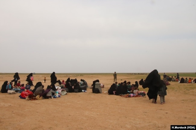 Women gather to receive humanitarian aid while they wait for transport to overcrowded Syrian camps, near Baghuz in Deir el-Zour, Syria, Feb. 26, 2019. (H.Murdock/VOA)