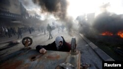 A Palestinian protester takes cover during clashes with Israeli troops at a protest against U.S. President Donald Trump's decision to recognize Jerusalem as the capital of Israel, near the Jewish settlement of Beit El, near the West Bank city of Ramallah,