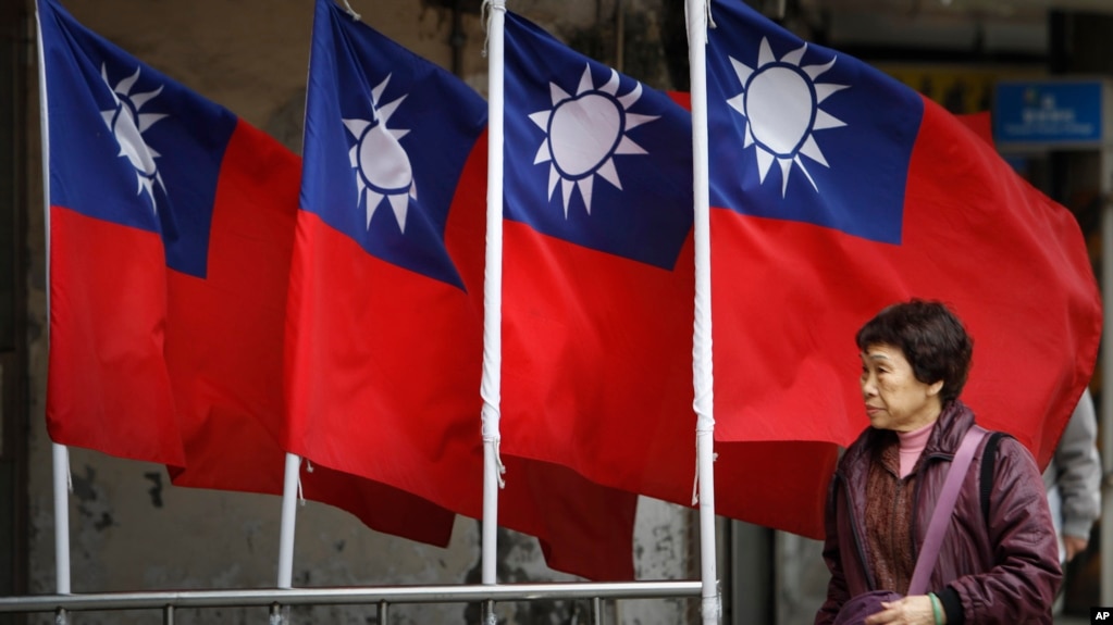 资料照：一名妇女走过台北街道旁飘扬的台湾旗帜。(photo:VOA)