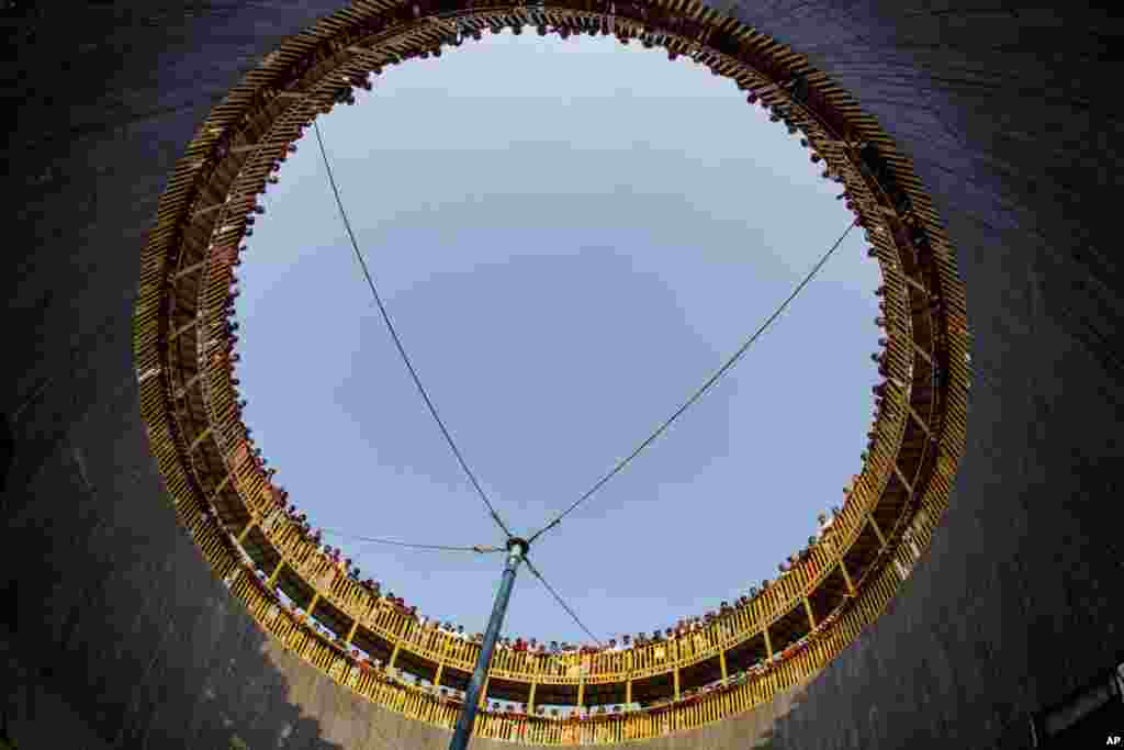 People watch Indian daredevils perform stunts in the well of death at Sangam, the confluence of the rivers Ganges, Yamuna and mythical Saraswati, in Allahabad, India.