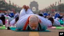 Indian Prime Minister Narendra Modi lies down on a mat as he performs yoga along with thousands of Indians on Rajpath, in New Delhi, India, Sunday, June 21, 2015. Millions of yoga enthusiasts are bending their bodies in complex postures across India as th