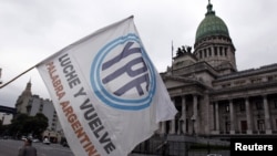 Un hombre agita una bandera con el logo de YPF en frente del congreso argentino, en Buenos Aires. Repsol ha puesto una demanda ante el Banco Mundial por este caso.