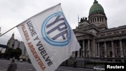 Un hombre agita una bandera con el logo de YPF en frente del congreso argentino, en Buenos Aires, donde esta maduraga de jueves fue aprobado el decreto de expropiación de YPF.