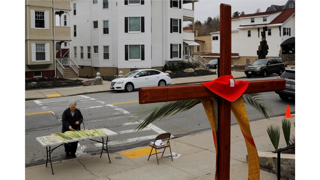 Seorang umat paroki mengambil daun palem di luar Gereja Katolik Sakramen Suci pada perayaan Minggu Palma di tengah wabah COVID-19 di Worcester, Massachusetts, 5 April 2020. (Foto: Reuters)