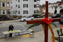 Seorang umat paroki mengambil daun palem di luar Gereja Katolik Sakramen Suci pada perayaan Minggu Palma di tengah wabah COVID-19 di Worcester, Massachusetts, 5 April 2020. (Foto: Reuters)