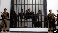 Yemeni soldiers stand guard as suspected al-Qaida militants, behind bars, attend a court hearing in Sanaa, Yemen, March, 4, 2013. 