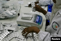 FILE - Employees inspect medication tablets in Africa.