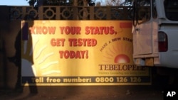 FILE - The shadow of a pedestrian is cast over a banner for a HIV testing center in Gaborone, Botswana.