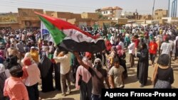 A Sudanese demonstrator waves a national flag during a protest against the October 2021 military coup, in the capital Khartoum, Jan. 13, 2022. 