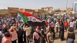 Seorang demontran mengibarkan bendera Sudan dalam aksi protes di Khartoum, pada 13 Januari 2022. Massa menentang kudeta militer yang terjadi pada Oktober 2021. (Foto: AFP)