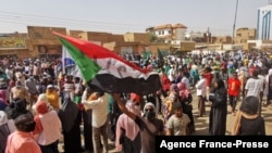 Un Soudanais brandit le drapeau national lors d'une manifestation contre le coup d'État militaire d'octobre 2021, dans la capitale Khartoum, le 13 janvier 2022. 