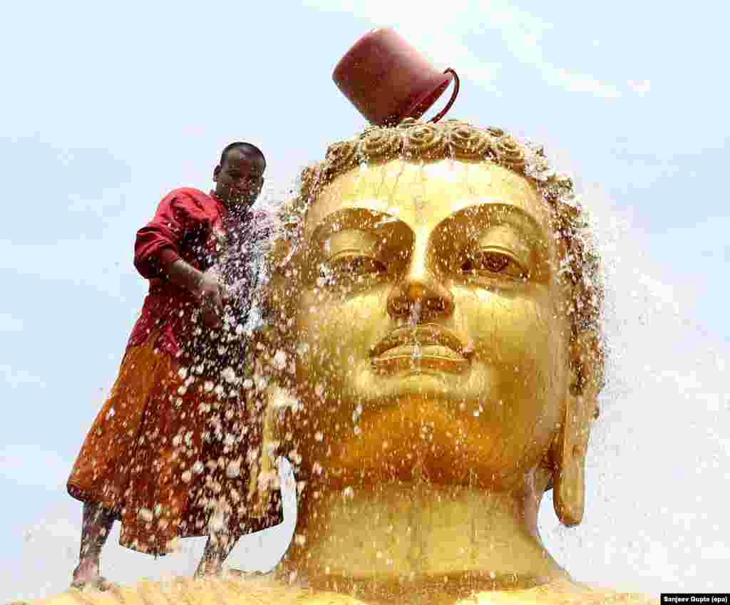 Seorang pendeta Buddha membersihkan patung Buddha menjelang peringatan kelahiran Buddha di kuil Bhopal, India.