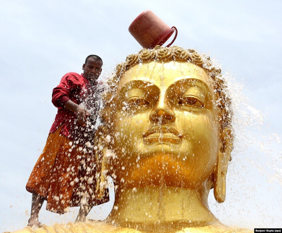 A Buddhist monk cleans the statue of Lord Buddha ahead of his birth anniversary in a monastery in Bhopal, India.