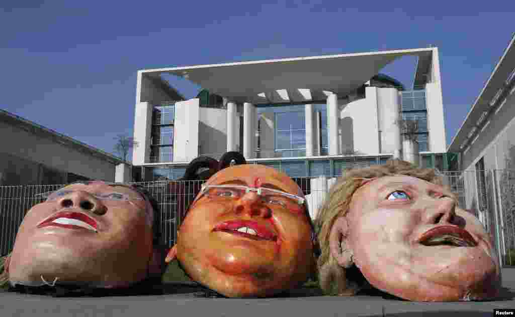 Caricature masks of (L-R) German Economy Minister Philipp Roesler, Environment Minister Peter Altmaier and Chancellor Angela Merkel are placed in front of the Chancellery during a protest against carbon dioxide emission, in Berlin.