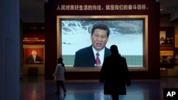 FILE - Chinese President Xi Jinping is seen on screen near the slogan "The people's yearning for a better life is the goal we strive for" at the Museum of the Communist Party of China in Beijing, China, Nov. 12, 2021. 