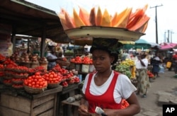 FILE - A woman sells skinned pawpaw, papaya, as she walks in a market on World Food Day in Lagos, Nigeria, Oct. 16, 2012.