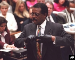 Johnnie Cochran puts on a pair of gloves Sept. 27, 1995, to remind the jury in the O.J. Simpson murder trial that the gloves Simpson tried on did not fit.