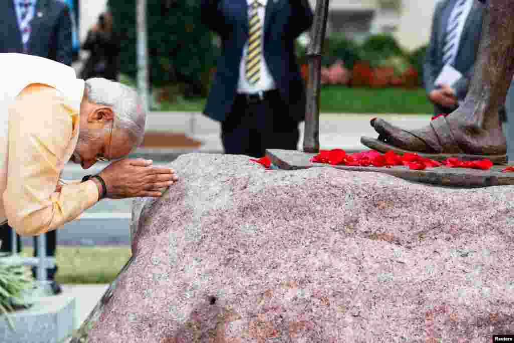India's Prime Minister Narendra Modi bows his head after scattering flower petals at the feet of the Mahatma Gandhi Statue outside the Indian Embassy in Washington, Sept. 30, 2014. 