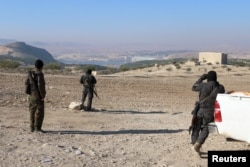 Kurdish fighters from the People's Protection Units (YPG) stand near the Tishrin dam, after they captured it from Islamic State militants, south of Kobani, Syria, Dec. 27, 2015.