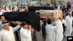 FILE - Mourners carry the coffins of victims of a suicide bombing, in the Shula neighborhood of Baghdad, Iraq, Oct. 12, 2014.
