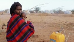 A refugee woman and her child from Somalia sit with their belongings outside Ifo refugee camp in Dadaab, near the Kenya-Somalia border