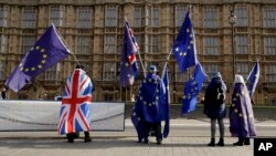 Pro-EU membership supporters hold European Union flags as they protest against Brexit across the street from the Houses of Parliament in London, Tuesday, Jan. 30, 2018.