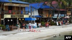 FILE - Tourists walk along a beach on Koh Rong island in Sihanoukville province on October 31, 2019. (Photo by TANG CHHIN Sothy / AFP)