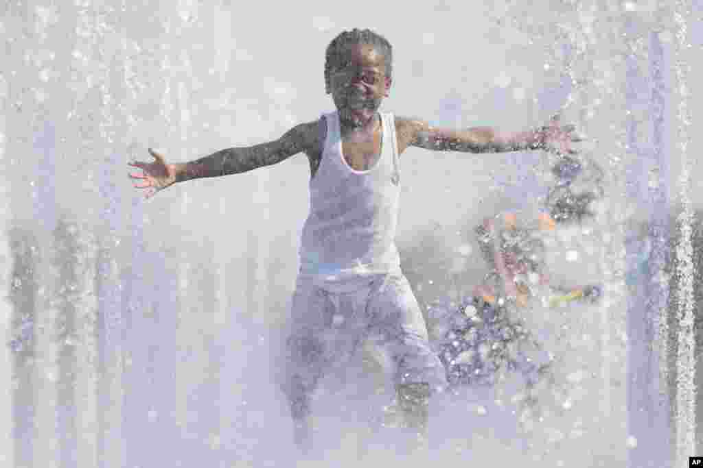 Kaydann Marshall runs through a park fountain in Cincinnati, Ohio, May 5, 2015.Temperatures rose past 80 degrees Fahrenheit for the second consecutive day as warmer weather settled into the region.