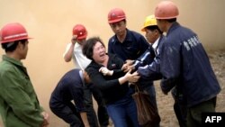 Huang Sufang (C) attempts to protect her home as workers move in for demolition orders in Yangji village, Guangzhou, south China's Guangdong province on March 21, 2012. 