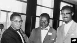 Joseph Kasavubu, à gauche, chef du parti Abako, et Patrice Lumumba, chef du Mouvement national du Congo (MNC), serrent la main dans le hall du Parlement du Congo à Léopoldville, le 20 juin 1960.