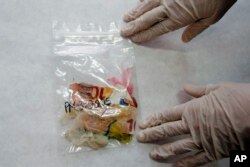 FILE - Cristina Cattaneo checks victims' personal belongings in a lab in Milan, Italy, Sept. 19, 2016.