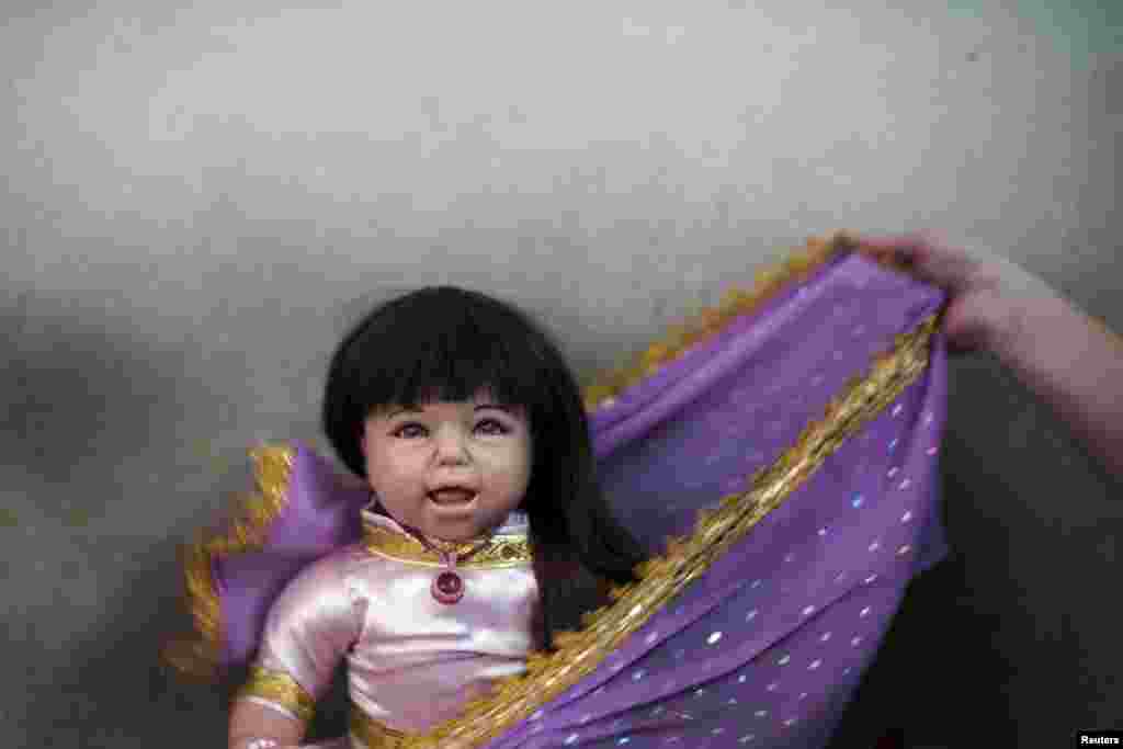 A devotee dresses up her "child angel" doll near Wat Bua Khwan temple in Nonthaburi, Thailand, Jan. 26, 2016. A craze for lifelike dolls thought to bring good luck is sweeping Thailand, reflecting widespread anxiety as the economy struggles and political uncertainty persists nearly two years after a coup.