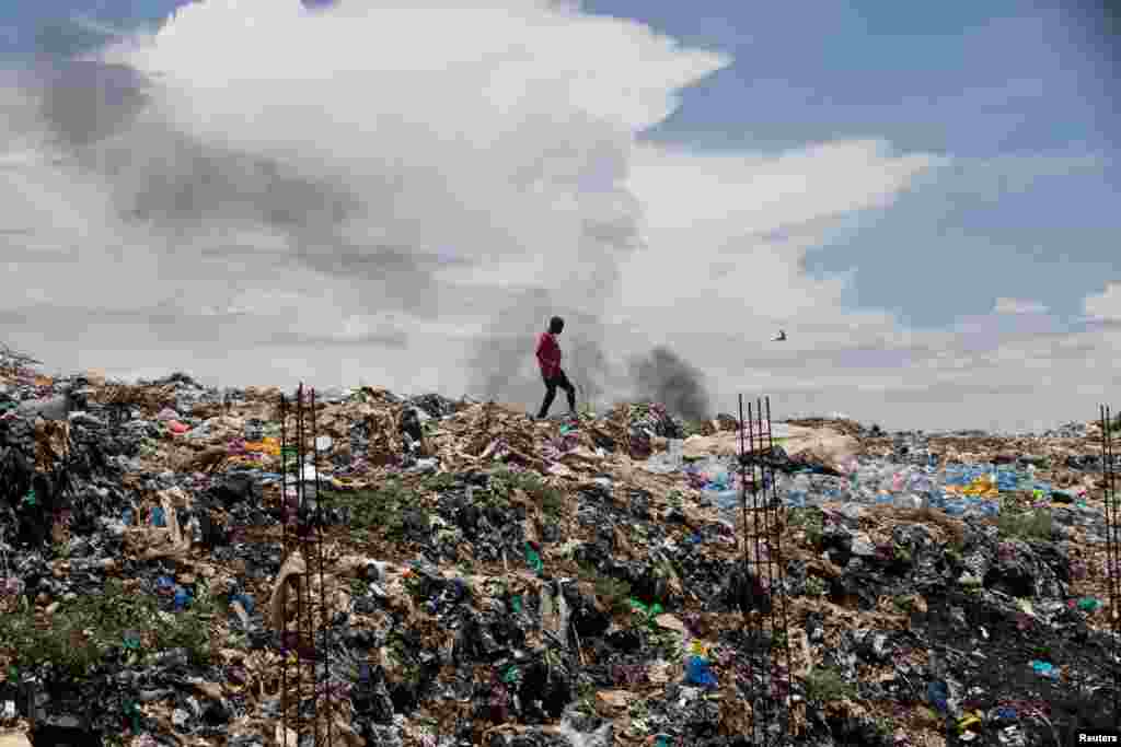 A man walks on top of a garbage dump in the city of Kisumu, Kenya.