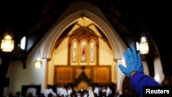 Un devoto levanta su mano enguantada durante la reapertura de los servicios religiosos en persona después de casi 18 meses de servicios virtuales debido a la pandemia de la enfermedad del coronavirus (COVID-19) en la iglesia Grant AME en Boston, el 3 de octubre de 2021.