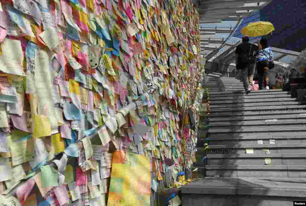 Thousands of colourful notes are displayed on &quot;Lennon Wall&quot; as a couple carrying a yellow umbrella, a symbol of the Occupy Central civil disobedience movement, walks past at the Admiralty protest site in Hong Kong.