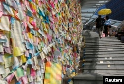 Thousands of colourful notes are displayed on the "Lennon Wall" as a couple carrying a yellow umbrella, a symbol of the Occupy Central civil disobedience movement, walks past at the Admiralty protest site in Hong Kong, Nov. 17, 2014.